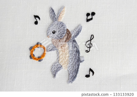 Embroidery of a gray rabbit dancing with a tambourine 133133920