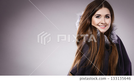 Happy woman wearing dark poncho with hood Happy woman wearing dark poncho with hood 133135646