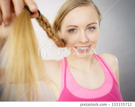 Happy woman looking at her hair ends Happy woman looking at her hair ends 133135712