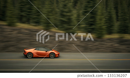 Low-profile orange sports car is racing along a 133136207