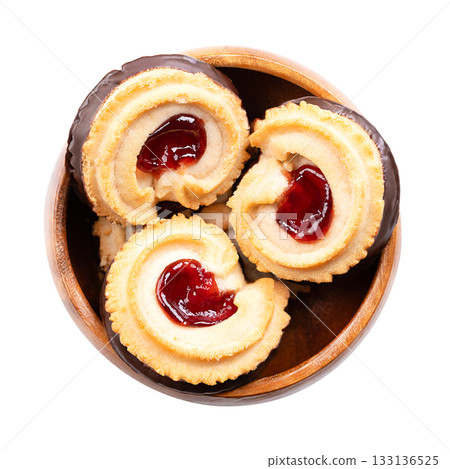 Jam filled tea biscuits, shortbread cookies, in a wooden bowl. Crumbly biscuits, made from high ratio of butter, along with sugar and flour, red jam in the center, and chocolate dipped at the bottom. 133136525
