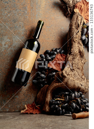 Bottle of red wine with blue grapes on a rusty background. Bottle of red wine with blue grapes on a rusty background. 133136743