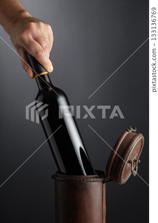 Sommelier places a bottle of red wine in an old wooden box. Sommelier places a bottle of red wine in an old wooden box. 133136769