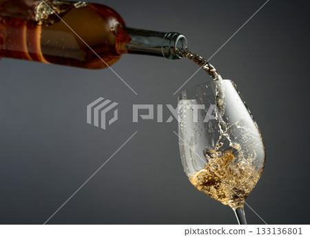 Pouring white wine from a bottle into a glass. 133136801