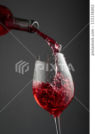 Pouring pink wine from a bottle into a glass. Pouring pink wine from a bottle into a glass. 133136802