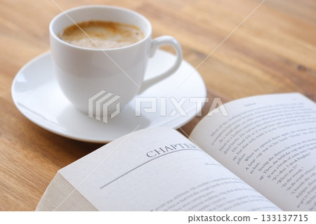 An image of enjoying reading while drinking coffee with an open book (Western book) and a coffee cup with coffee in it. An image of enjoying reading while drinking coffee with an open book (Western book) and a coffee cup with coffee in it. 133137715