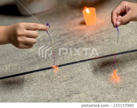 Two children's hands holding sparklers 133137980