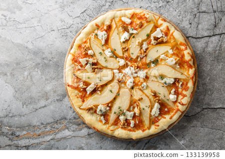 Sweet spicy pear pizza with blue cheese, walnuts, mozzarella and thyme close-up on a wooden board. Horizontal top view 133139958
