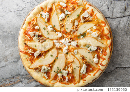 Honey pear pizza with blue cheese, nuts, mozzarella and thyme close-up on a wooden board. Horizontal top view 133139960