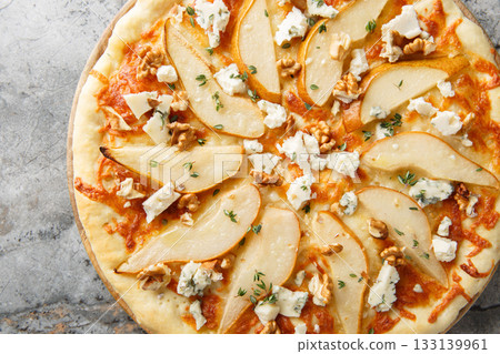 Delicious pizza with pears, gorgonzola cheese, walnuts and herbs closeup on the wooden board. Horizontal top view 133139961
