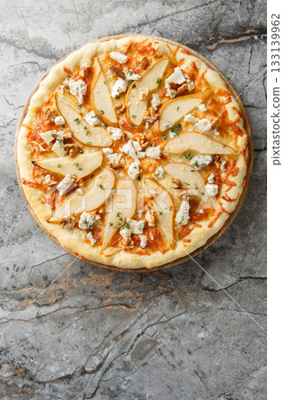 Pizza with pear, blue cheese, walnuts and thyme close-up on a wooden board. Vertical top view Pizza with pear, blue cheese, walnuts and thyme close-up on a wooden board. Vertical top view 133139962