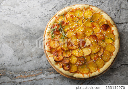 Vegetarian Potato rosemary pizza sprinkled with coarse salt and baked until crispy close-up on a wooden board. Horizontal top view 133139970