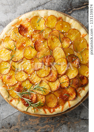 Potato and Rosemary Pizza is made with thinly sliced potatoes drizzled in olive oil and fresh rosemary and baked until crispy closeup on the wooden board. Vertical top view Potato and Rosemary Pizza is made with thinly sliced potatoes drizzled in olive oil and fresh rosemary and baked until crispy closeup on the wooden board. Vertical top view 133139974