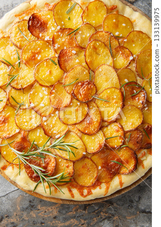 Delicious potato rosemary pizza with cheese and coarse salt close-up on a wooden board on the table. Vertical top view Delicious potato rosemary pizza with cheese and coarse salt close-up on a wooden board on the table. Vertical top view 133139975