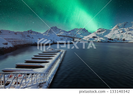 Empty pier in small fishing village on Sundstraumen strait and Kakern Bridge at night with Northern Lights. Empty pier in small fishing village on Sundstraumen strait and Kakern Bridge at night with Northern Lights. 133140342
