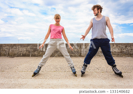 Two people exercise stretch outdoor on rollerblades. Two people exercise stretch outdoor on rollerblades. 133140682