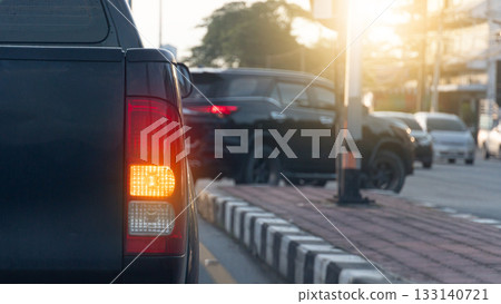 Rear side of pickup car black color with turn on signal right. Park to wait for a U-turn. Car in front is about to make a U-turn. Blurred of many cars are driving by. 133140721
