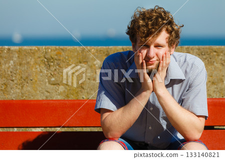 Tired exhausted man sitting on bench by sea ocean. Tired exhausted man sitting on bench by sea ocean. 133140821