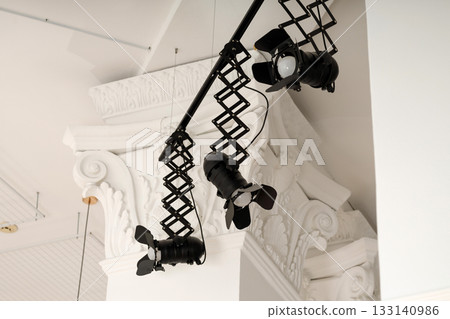 Professional stage lighting fixtures mounted on a ceiling with ornate architectural details 133140986