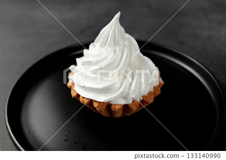 cake basket with protein cream in a black round plate on a black background 133140990