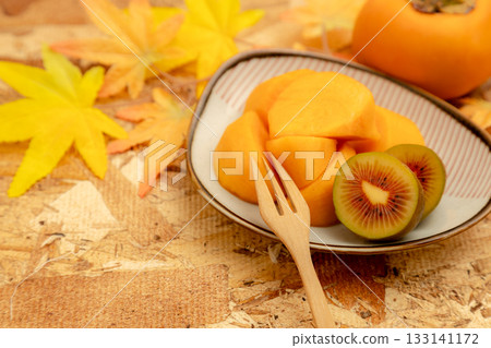 Autumn taste of persimmon and kiwi. Cross section of red kiwi. Autumn taste of persimmon and kiwi. Cross section of red kiwi. 133141172