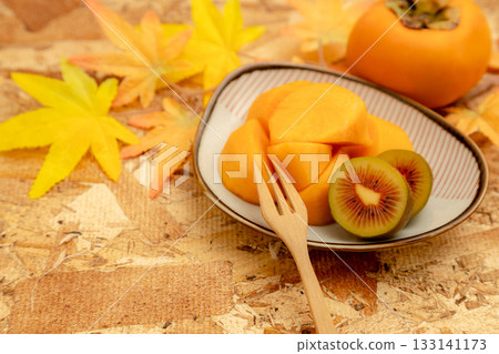Autumn taste of persimmon and kiwi. Cross section of red kiwi. Autumn taste of persimmon and kiwi. Cross section of red kiwi. 133141173