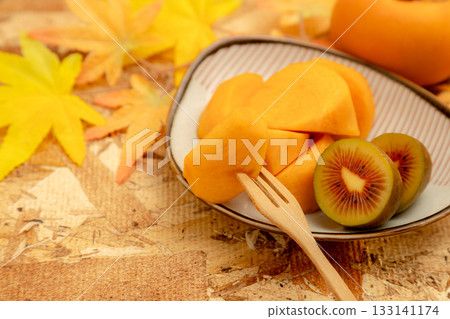 Autumn taste of persimmon and kiwi. Cross section of red kiwi. Autumn taste of persimmon and kiwi. Cross section of red kiwi. 133141174