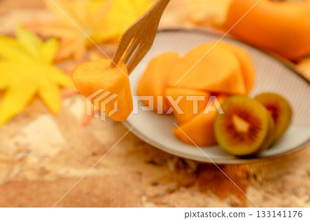 Autumn taste of persimmon and kiwi. Cross section of red kiwi. Autumn taste of persimmon and kiwi. Cross section of red kiwi. 133141176