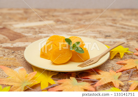 Persimmons, a taste of autumn, served on a plate with sliced persimmons, mint leaves and a fork 133141751