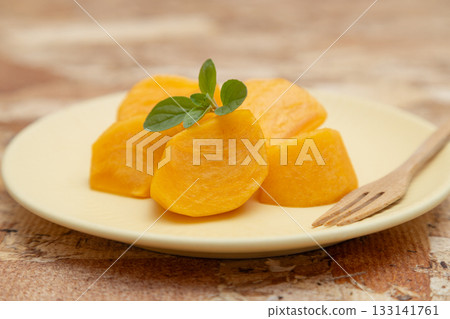 Persimmons, a taste of autumn, served on a plate with sliced persimmons, mint leaves and a fork 133141761