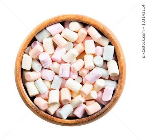 Multi-colored mini marshmallows, in wooden bowl. Pastel colored bits of a confectionery made from sugar, water and gelatin, whipped to a solid, soft consistency. Used as topping. Isolated, from above. Multi-colored mini marshmallows, in wooden bowl. Pastel colored bits of a confectionery made from sugar, water and gelatin, whipped to a solid, soft consistency. Used as topping. Isolated, from above. 133143214