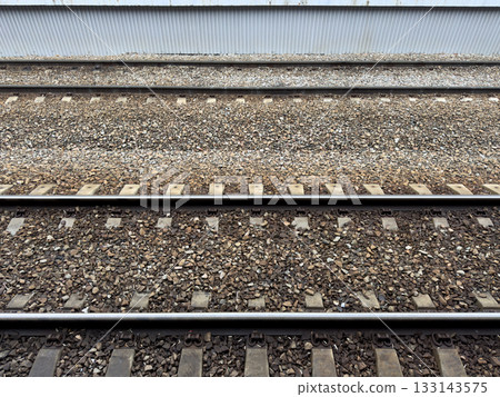 Railroad tracks covered with crushed stone. View from the platform onto the tracks for arriving trains at the station. Concept of railroads as means of transporting people and goods 133143575