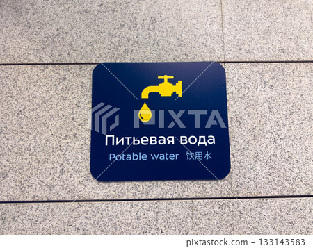 Potable Water sign on wall. Sign in Russian, English, and Chinese indicates the location of the drinking fountain at the airport. International interaction with multilingual signs Potable Water sign on wall. Sign in Russian, English, and Chinese indicates the location of the drinking fountain at the airport. International interaction with multilingual signs 133143583