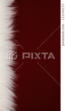 A luxurious strip of soft white fur creates a striking contrast against a rich, deep red velvet background with ample copy space and low-key lighting. 133144175