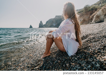 Woman Contemplating the Ocean on a Rocky Beach 133145057