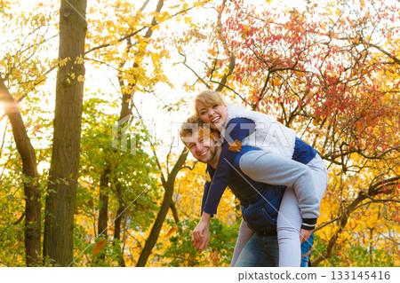 Man giving piggyback ride to woman in park Man giving piggyback ride to woman in park 133145416