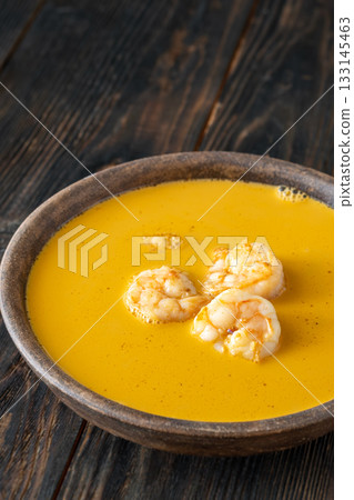 Clay bowl of creamy shrimp bisque served warmly on rustic wooden table 133145463