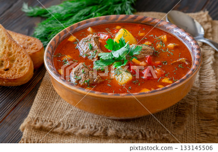 Traditional Bogracs stew garnished with parsley served with toasted bread beside 133145506