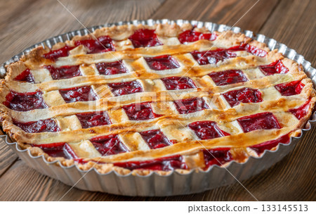 Freshly baked lattice-top cherry pie resting beautifully on rustic wooden surface Freshly baked lattice-top cherry pie resting beautifully on rustic wooden surface 133145513