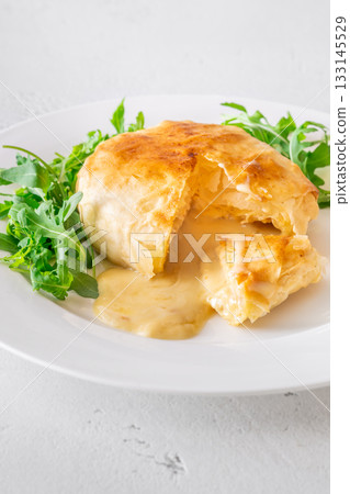 Melted Camembert en Croute with rosemary garnish and vibrant cranberry sauce accompaniment 133145529