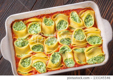 Golden baked lumaconi filled with ricotta and spinach resting in rich tomato sauce Golden baked lumaconi filled with ricotta and spinach resting in rich tomato sauce 133145546