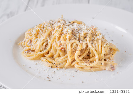 Creamy traditional carbonara served with grated parmesan on smooth white ceramic plate Creamy traditional carbonara served with grated parmesan on smooth white ceramic plate 133145551