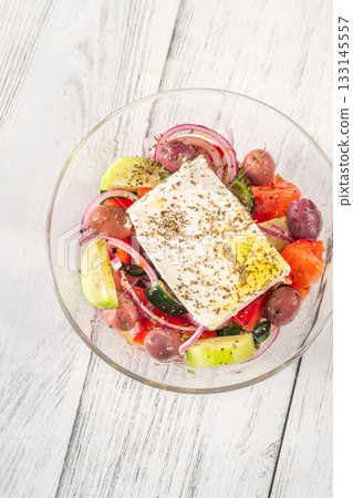 Fresh traditional Greek salad topped with thick feta slice served in glass bowl Fresh traditional Greek salad topped with thick feta slice served in glass bowl 133145557