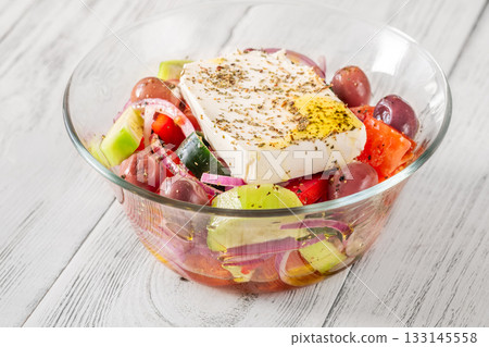 Fresh traditional Greek salad topped with thick feta slice served in glass bowl 133145558