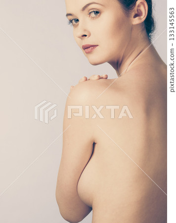 Bare woman covering her breast with hands 133145563