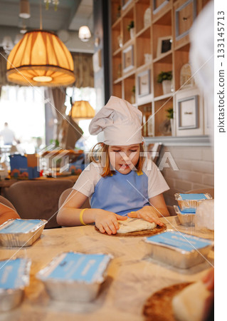 Kids enjoy cooking class making pizza in a cozy kitchen 133145713