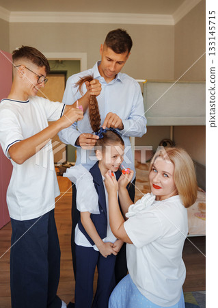 Family prepares little girl for special event with hairstyling and accessories 133145715