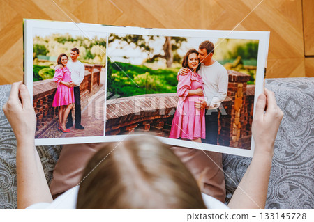 woman is holding and flipping through a photo book with a pregnancy photo shoot woman is holding and flipping through a photo book with a pregnancy photo shoot 133145728