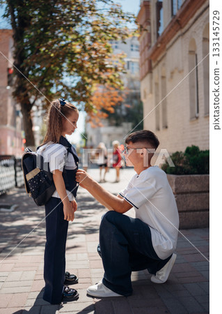 Father helps daughter with backpack before school on sunny morning Father helps daughter with backpack before school on sunny morning 133145729