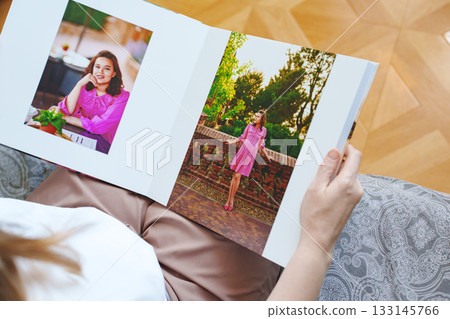 woman is holding and flipping through a photo book with a pregnancy photo shoot 133145766